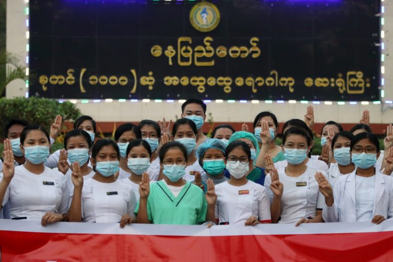 Striking medical staff hold up a three-finger salute in opposition to military rule at a government hospital in Nay Pyi Taw in February 2021. (AFP)