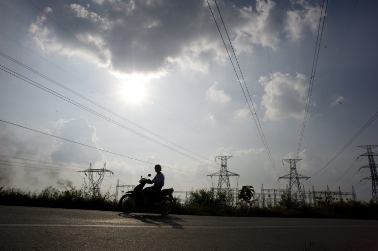 A man rides his motorbike past a power station in northern Yangon Region on November 22, 2014.(AFP)