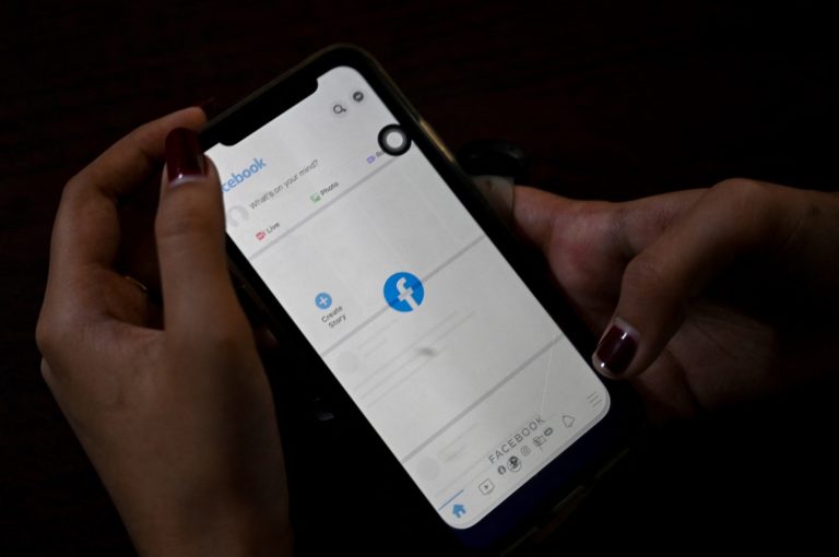 A woman uses her mobile phone to check Facebook in Yangon on February 4, 2021. (AFP)