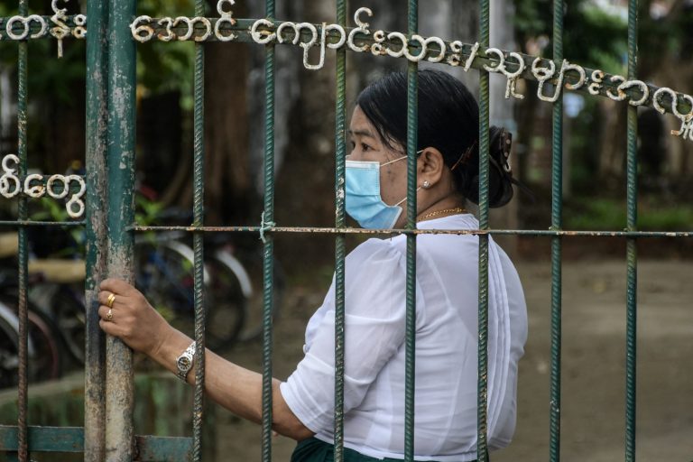 A school official stands behind the entrance of a school in the Rakhine State capital of Sittwe on June 1, 2021. (AFP)