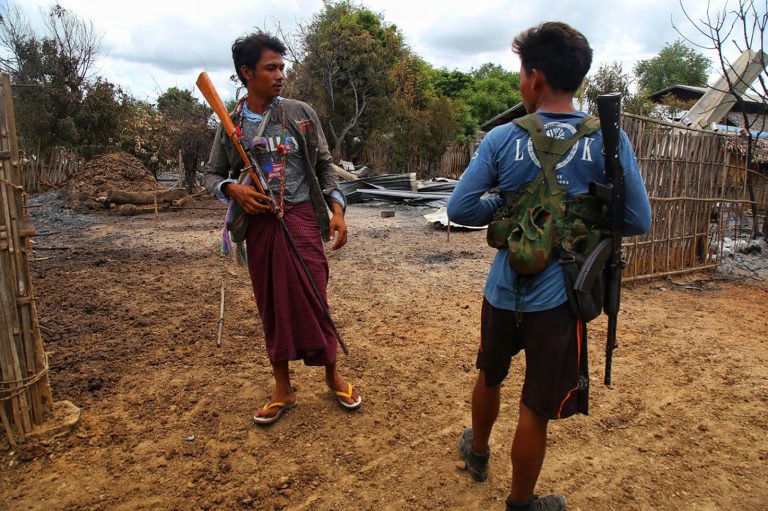 People’s Defence Force fighters stand next to burned debris after an attack by the military in a village in Sagaing Region on August 5, 2022. (AFP)