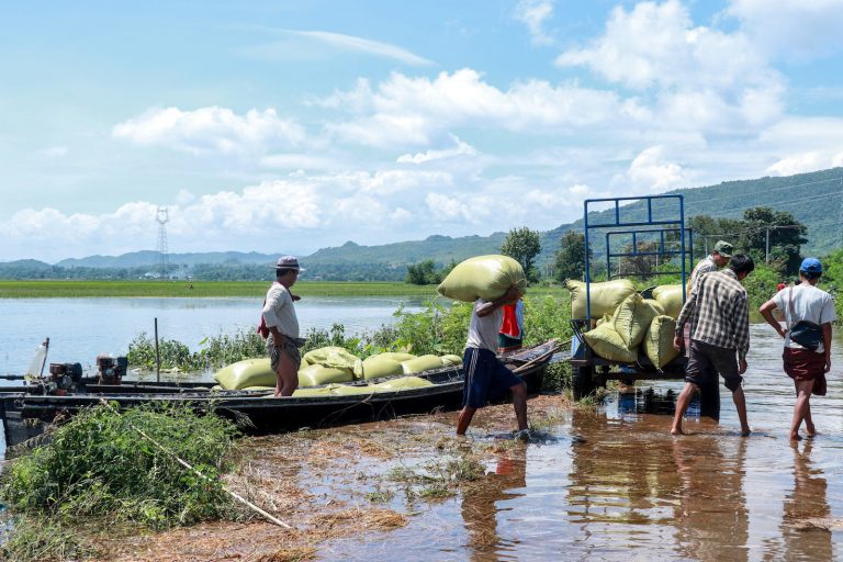 Farmers carry bags of rice next to flood waters as they evacuate their homes in Loikaw Township in September. (AFP)