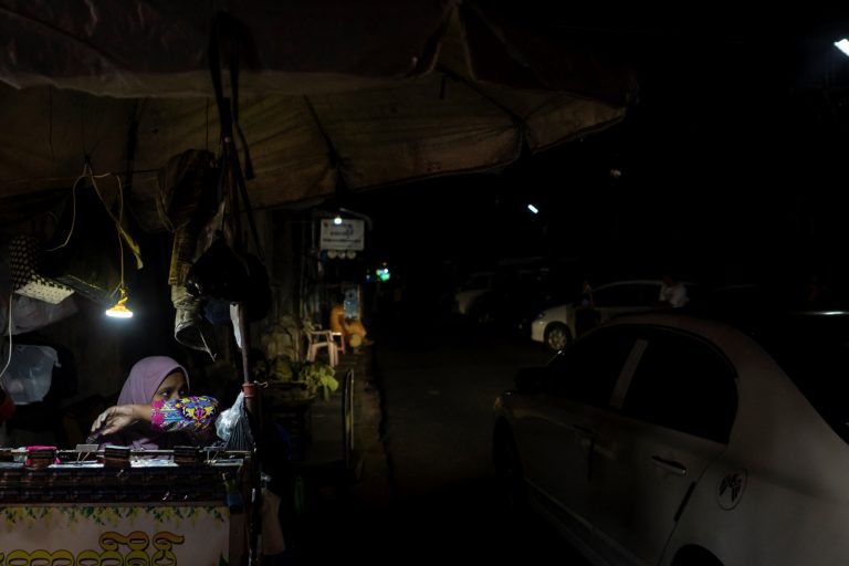 A vendor waits for customers at her roadside food stall during an electricity blackout in Yangon on February 1. (AFP)