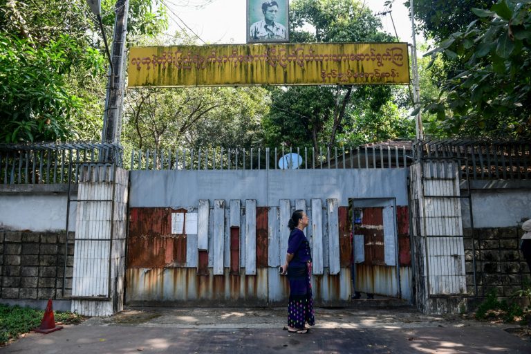 A woman stands outside the gates of the family house of detained state counsellor Daw Aung San Suu Kyi in Yangon on February 5, the day a junta court unsuccessfully tried to auction it for the third time. (AFP)
