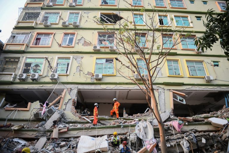 Rescue teams work to evacuate residents trapped under the rubble of a collapsed building in Mandalay on March 30. (AFP)