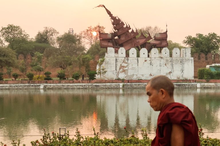 A monk walks past the damaged Mandalay Palace during sunset in Mandalay on March 31, three days after a deadly earthquake struck central Myanmar. (AFP)