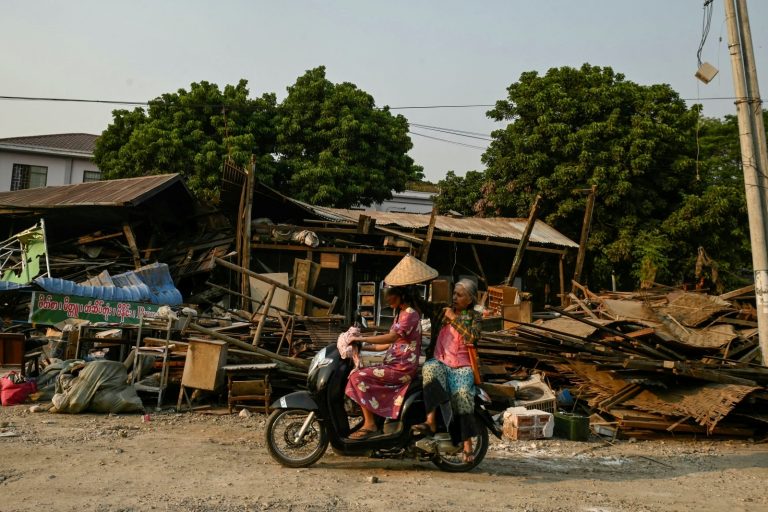 Women ride on a motorbike past collapsed buildings in Sagaing town on April 2, five days after a major earthquake struck central Myanmar. (AFP)