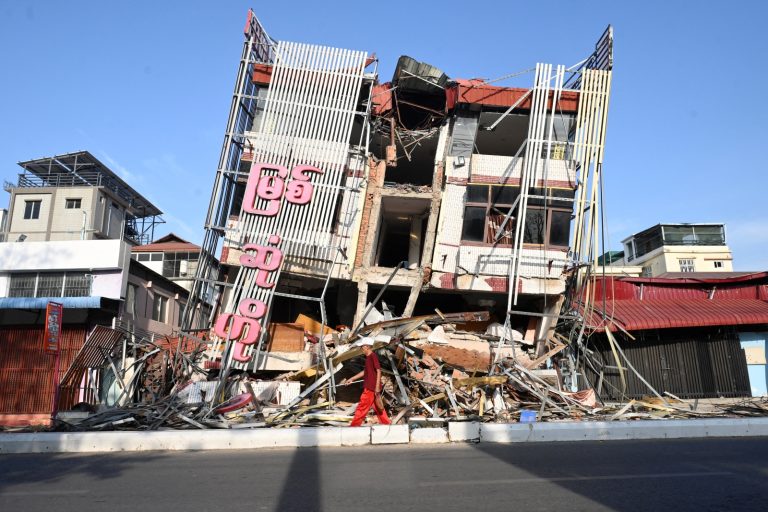 A man walks past a damaged building in Mandalay on April 13. (AFP)