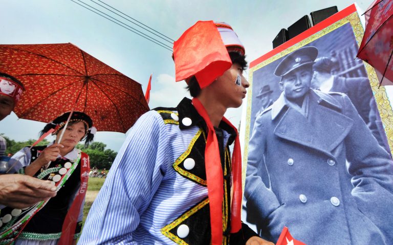 National League for Democracy supporters walk past a sign of Bogyoke Aung San at a rally led by Daw Aung San Suu Kyi in Myitkyina in 2015. (Steve Tickner)