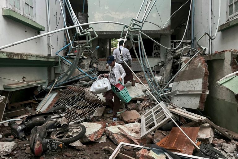A resident carries his belongings over the debris of a damaged building in Nay Pyi Taw on March 28. (AFP)