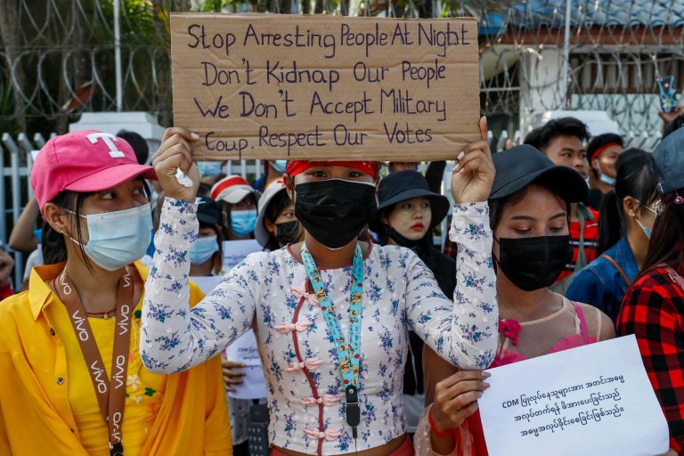 A protester outside the International Labour Organization office in Yangon holds up a sign decrying midnight arrests by security forces on February 17. (Frontier)