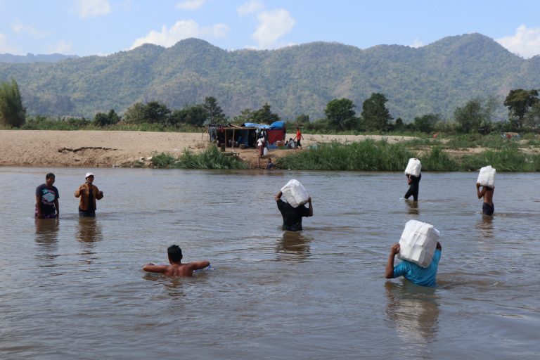 Karen refugees wade across the Moei River, which forms the border with Thailand, to receive aid supplies. (Frontier)