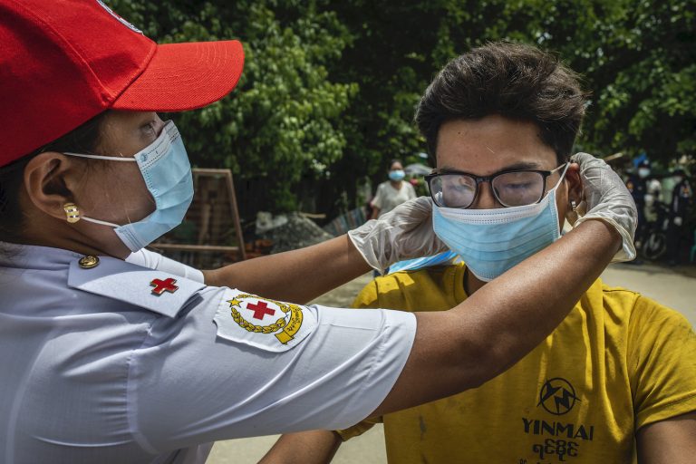 A Red Cross officer adjusts a man's mask in Mrauk-U on August 21. (Hkun Lat | Frontier)