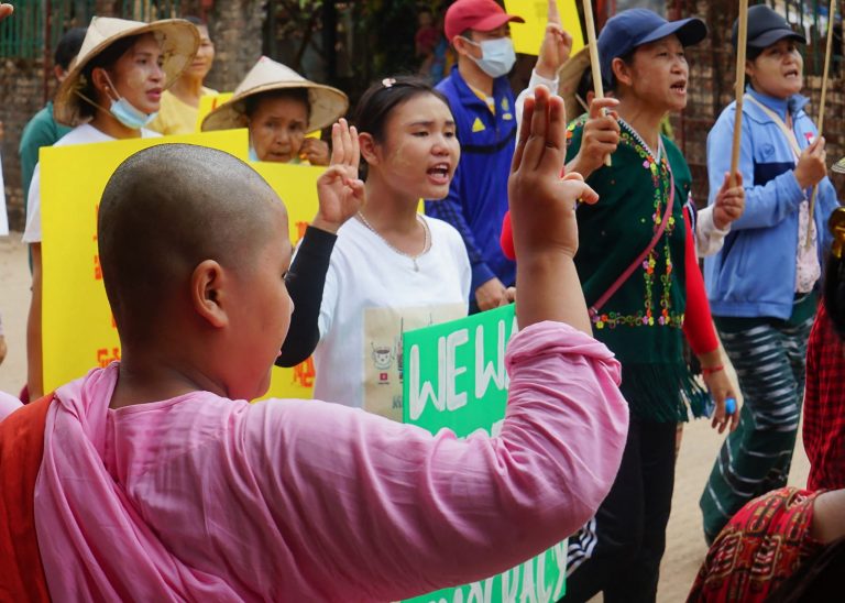 A young Buddhist novice nun holds up the three-finger salute to anti-coup protesters in Karen National Union-administered Dooplaya District, Kayin State, on April 2. (KNU / AFP)