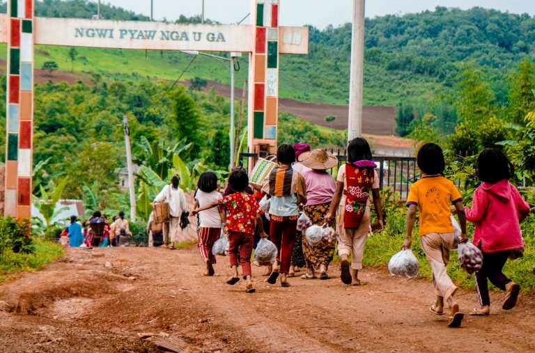 Villagers on June 10 carry food aid distributed by volunteers in Pankai village, in northern Shan State's Kutkai Township, where local authorities say villagers are struggling to obtain daily necessities due to continued conflict between the Tatmadaw and Northern Alliance. (MNWN / AFP)