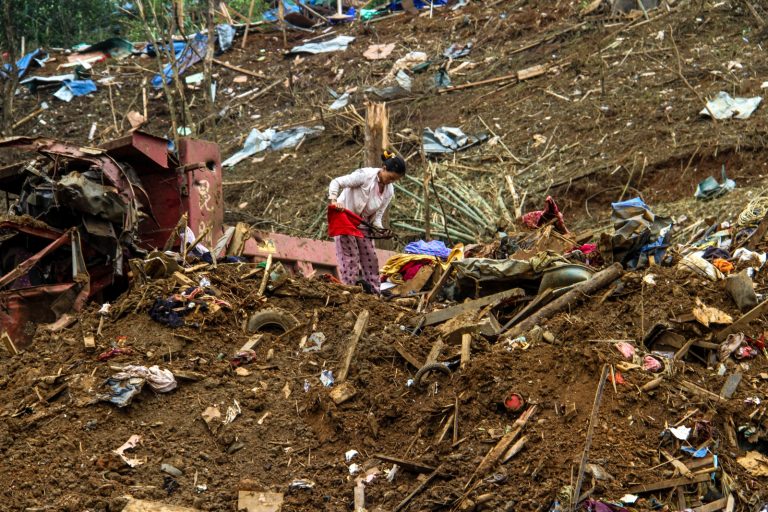 A woman looks through debris in the aftermath of a military strike on a camp for displaced people near the town of Laiza, in northern Kachin State, on October 11, 2023, two days after the attack that killed 29 people and wounded dozens. (AFP)