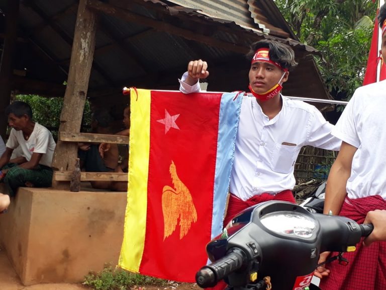 A young man campaigns with the flag of the Mon Unity Party in Mon State's Mudon Township on October 18. (Lawi Weng | Frontier)