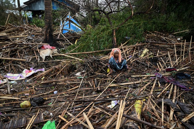 A Rohingya woman sits in her destroyed house at Basara camp in Sittwe on May 16, two days after Cyclona Mocha made landfall. (AFP)