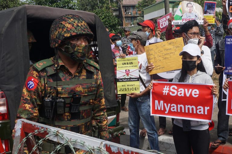 A soldier stands guard next to anti-coup protesters in Yangon on February 15, 2021. (AFP)