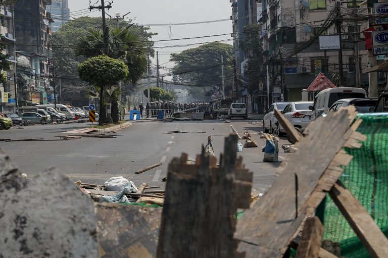 Police are seen above a barricade in Yangon on February 28. (Frontier)