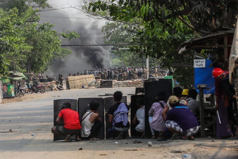 Protesters with makeshift shields face off against police and soldiers in Hlaing Tharyar on March 14, a day that saw at least 58 civilians killed, according to local volunteer medical groups. (Frontier)