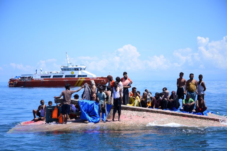 Rohingya refugees wait to be rescued from the hull of their capsized boat as a vessel of Indonesia’s National Search and Rescue Agency approaches in waters off Aceh province on March 21. (AFP)