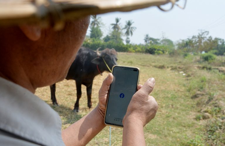 A farmer checks Facebook on his smartphone on March 16, shortly before the military regime cut mobile internet across Myanmar. (AFP)