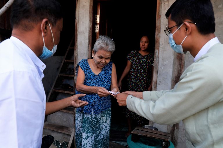 A Dawbon Township resident receives K20,000 from a local administrator under the government's cash transfer programme on July 25. (Nyein Su Wai Kyaw Soe | Frontier)