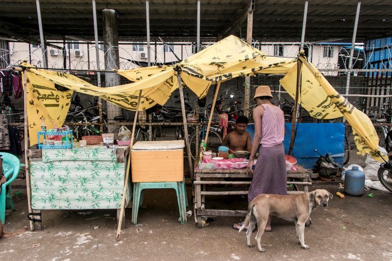 A man buys street food from a vendor in a poor community on the outskirts of Yangon on  May 21, 2021. (AFP)