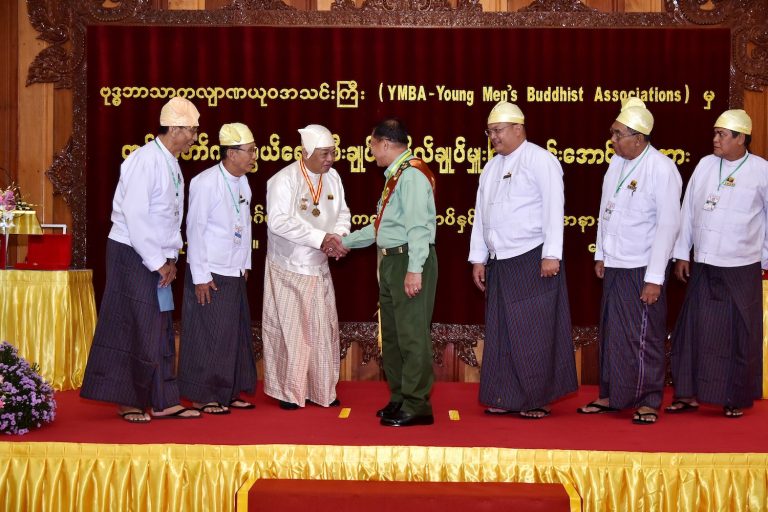 YMBA chair U Ye Htun shakes Senior General Min Aung Hlaing's hand after presenting him with an award and making him the group's patron for life in October 2019. (Supplied | CINDCS)