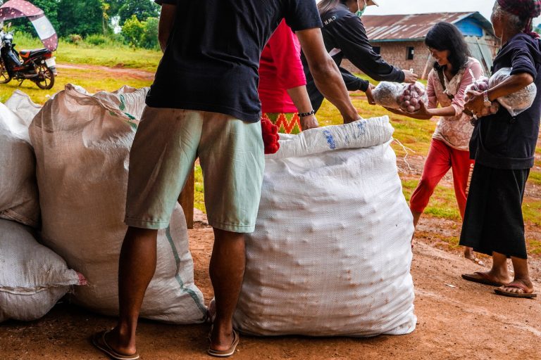 People receive food distributed by a volunteer group in a conflict-hit area of Kutkai Township, Shan State in June last year. (MNWM / AFP)