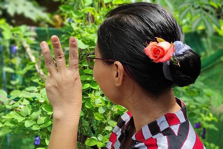 A woman in Yangon gives the three-finger salute while wearing flowers in her hair, as part of a social media campaign to mark the birthday of detained civilian leader Daw Aung San Suu Kyi on June 19. (Facebook, anonymous / AFP)