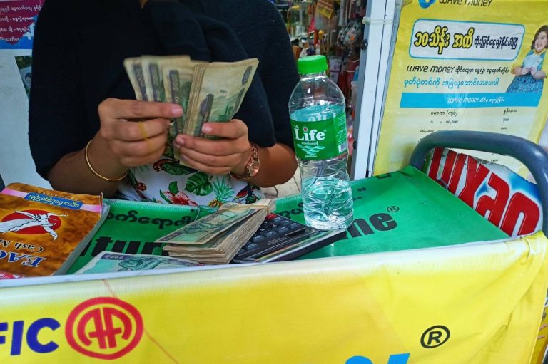 A Wave Money agent in Yangon counts cash before handing it over to a customer in May. Agents are charging 10 percent or more for cash withdrawals, in violation of company policy. (Frontier)