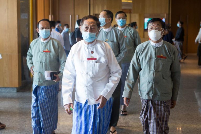 Chief election commissioner U Hla Thein (centre, in white) arrives at a meeting with political parties in Yangon on June 27 flanked by fellow commissioners. (Thuya Zaw | Frontier)