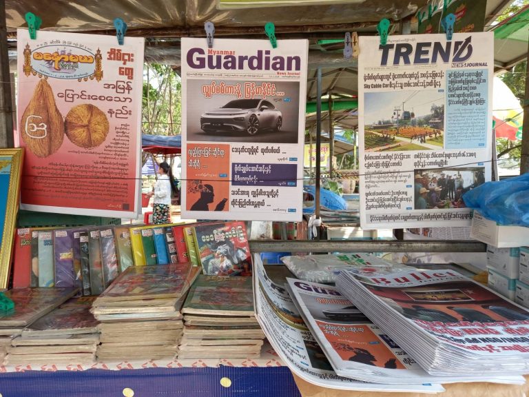 A newsstand sells a collection of state-approved newspapers and magazines. After most independent media was banned, papers like ultranationalist Hla Swe's Bullet News Journal (bottom right) have become best sellers. (Frontier)