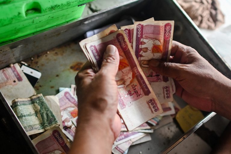 A shopkeeper counts the day's earnings at his shop in Yangon on March 21, 2020. (AFP)