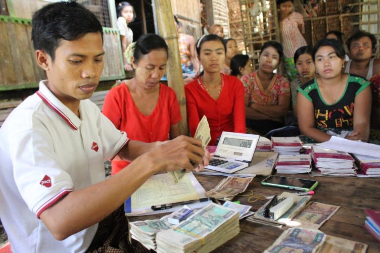 Borrowers watch an employee of PACT Global Microfinance Fund count money in a village in Dedaye Township, Ayeyarwady Region, in April 2015. (Frontier)